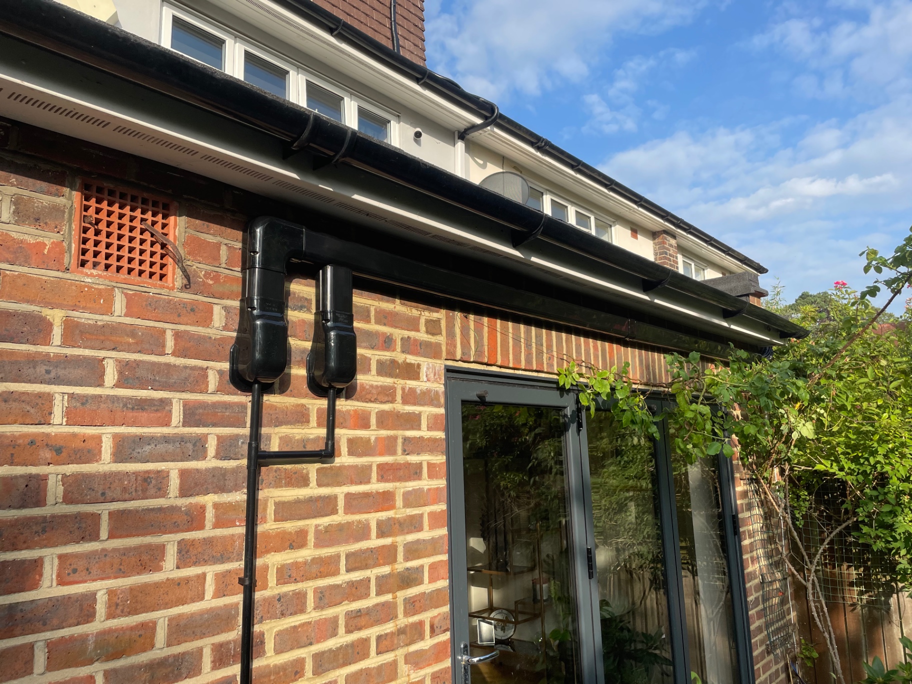 Neatly installed air conditioning pipework and condensate drain in black trunking on a house exterior