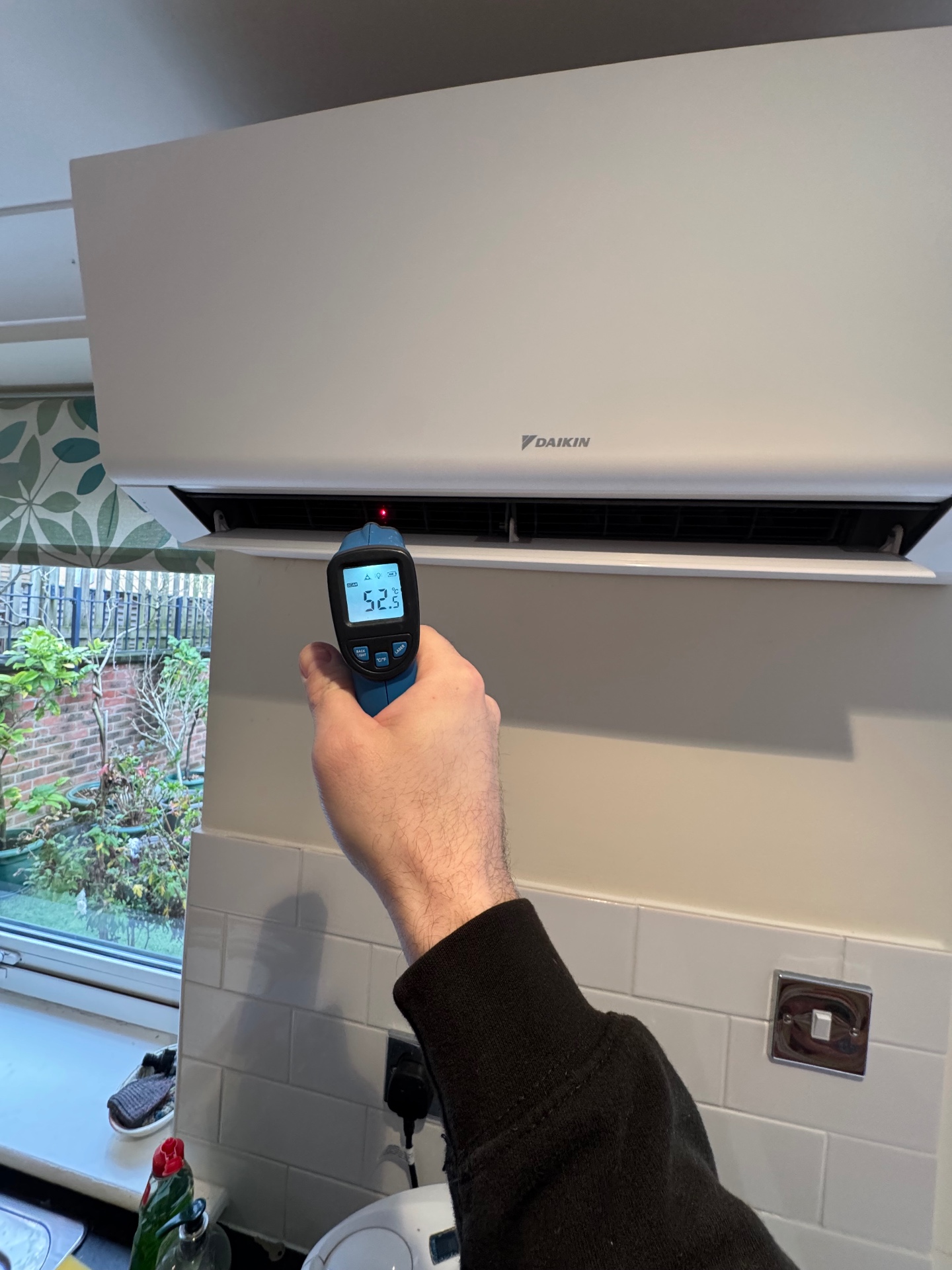 Engineer commissioning a Daikin wall-mounted air conditioning unit in a Surrey home