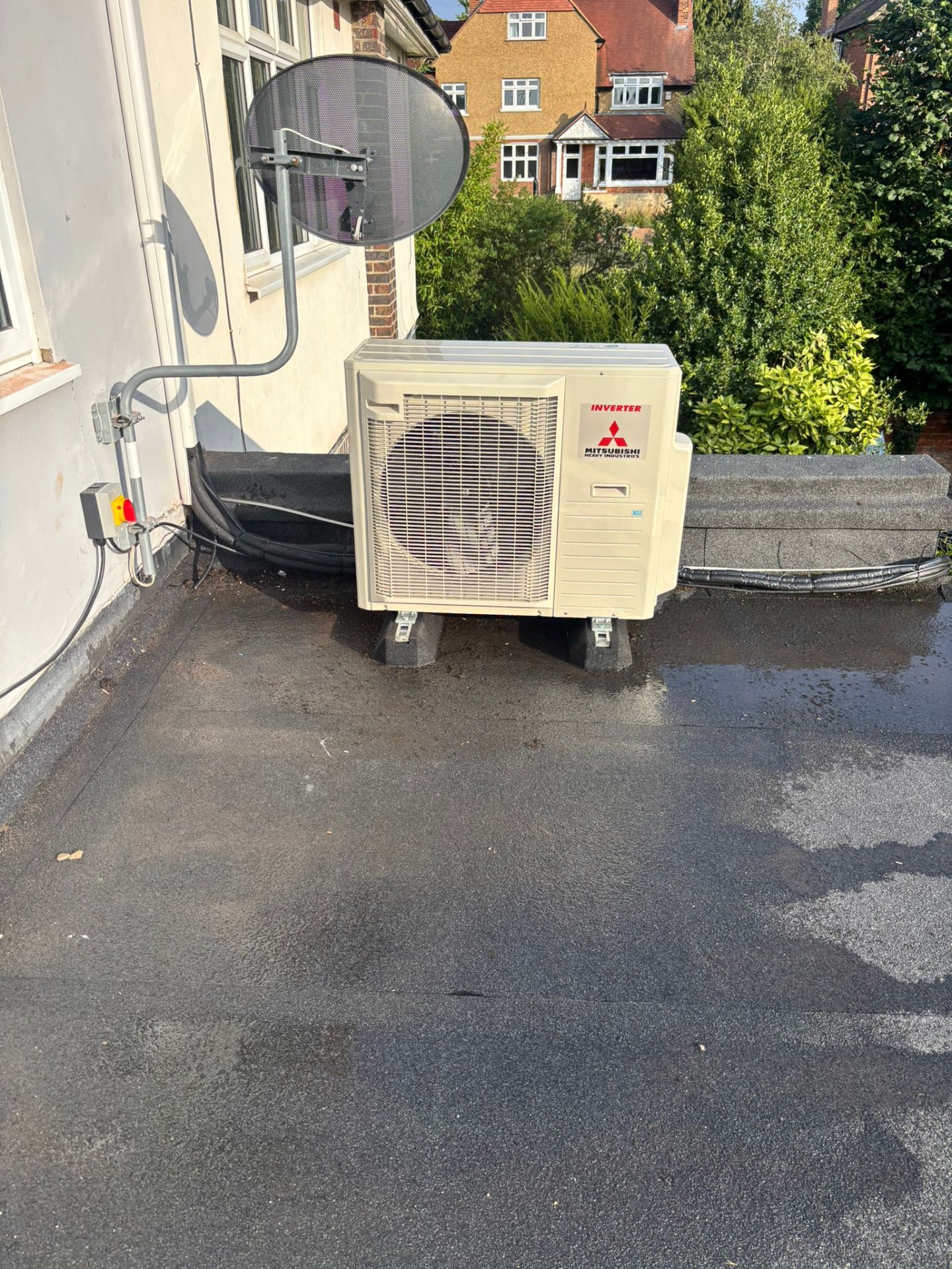 Mitsubishi Heavy Industries outdoor air conditioning unit on anti-vibration feet on a flat roof in Cheam