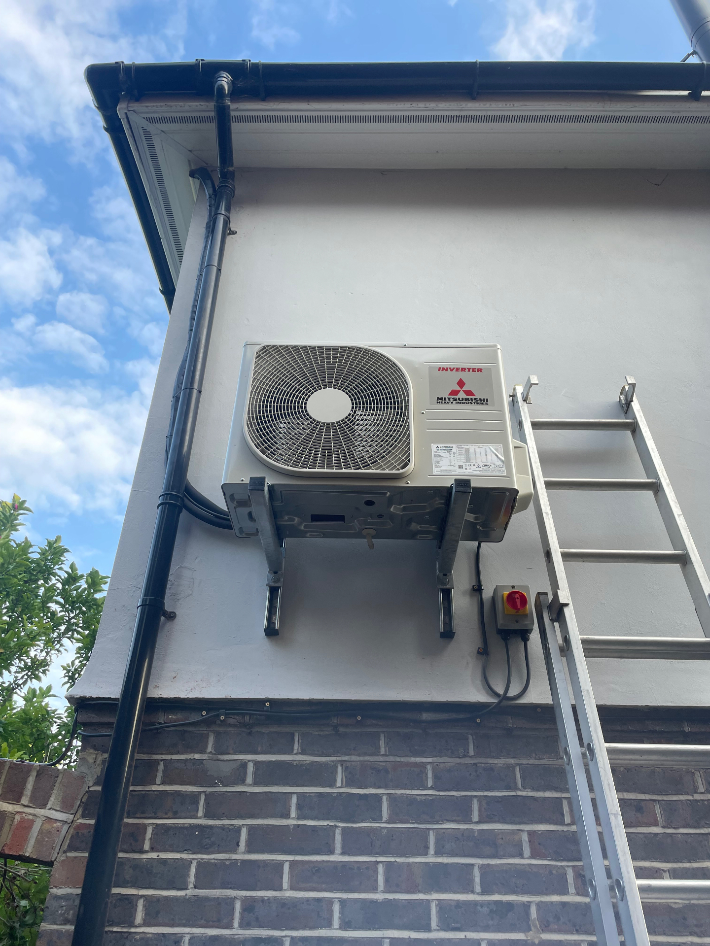 Outdoor air conditioning unit mounted on wall brackets at a house in Sutton