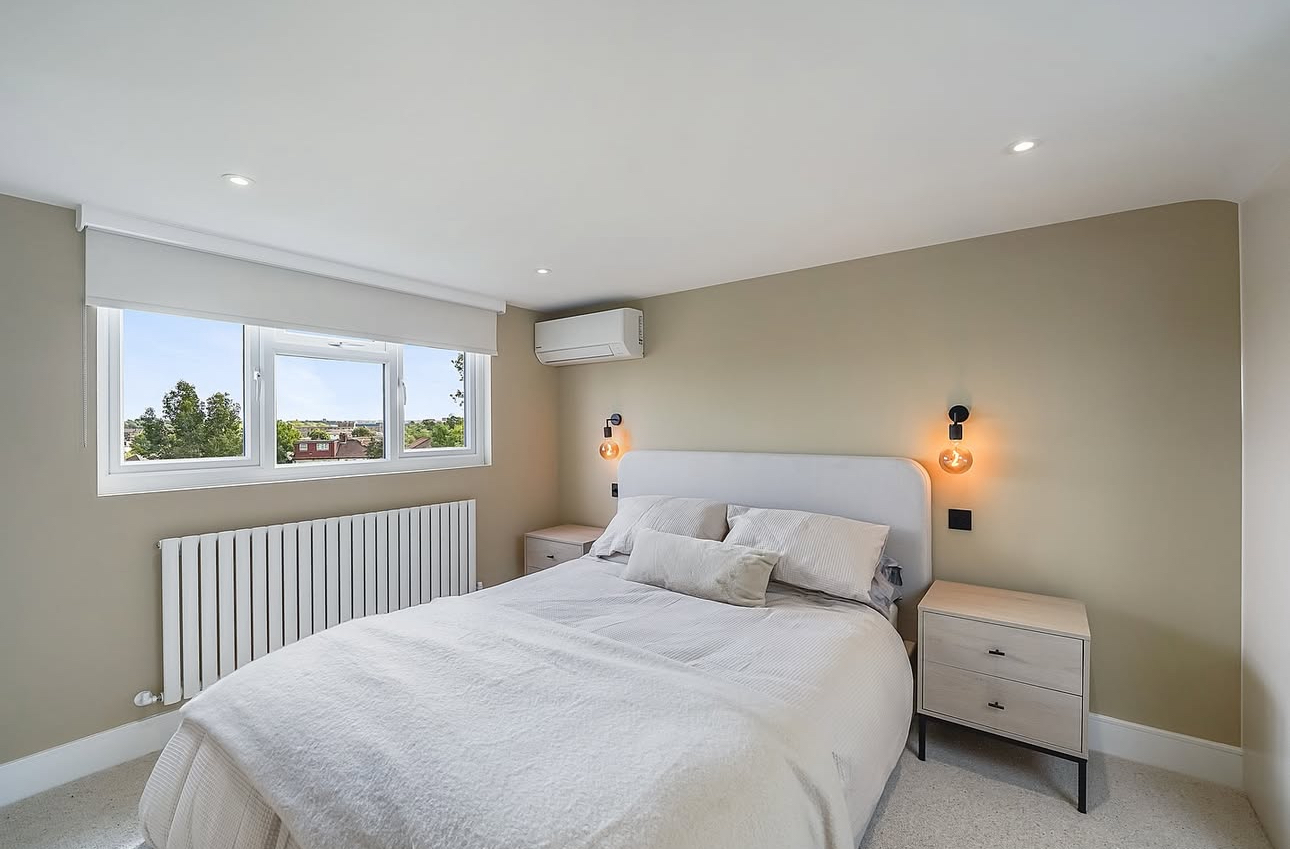 Wall-mounted air conditioning unit installed above the bed in a bedroom in Cheam