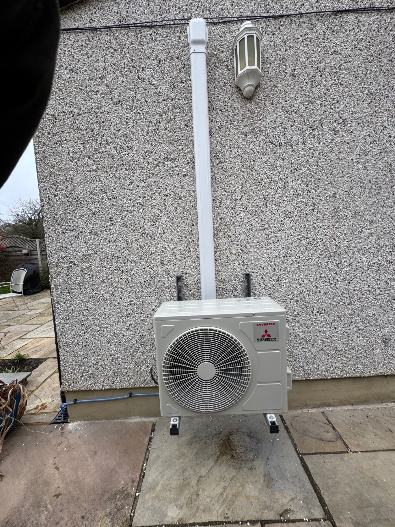 Mitsubishi Heavy Industries outdoor air conditioning unit with white trunking pipework on a rendered house wall